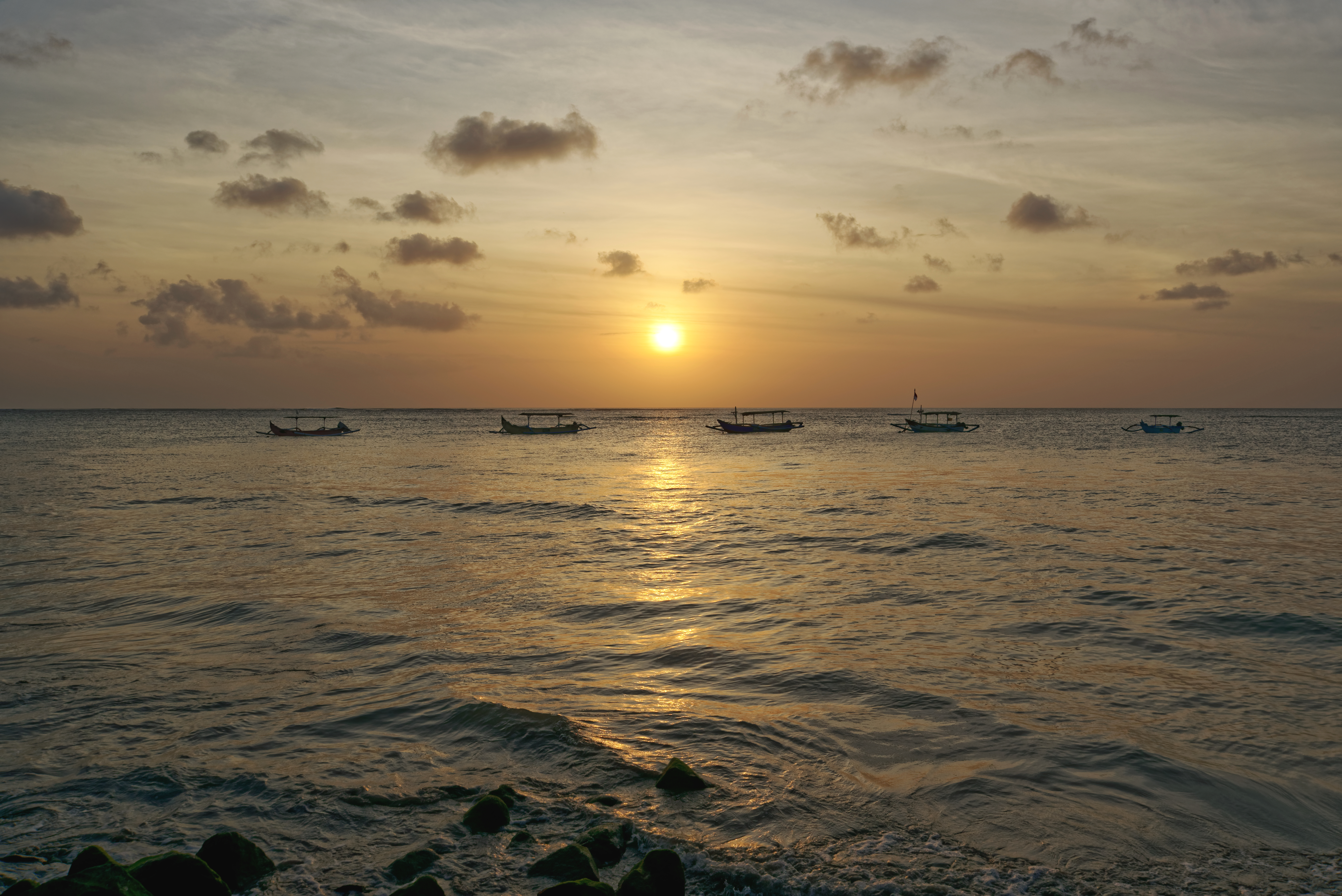 Sunset over Bali ocean horizon with small boat